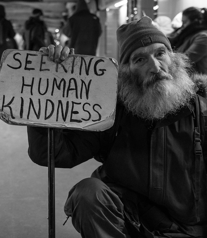 Man holding sign that states Seeking Human Kindness